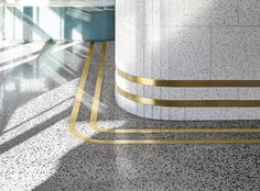 an airport lobby with marble floors and gold lines on the floor next to a large white pillar