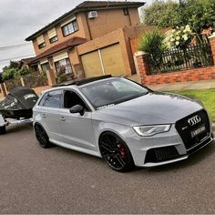 a silver car parked in front of a house next to a boat on the street