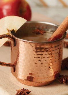 an apple and cinnamon stick in a copper mug