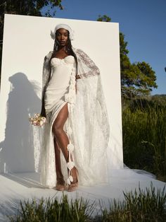 a woman in a white dress and veil standing next to a large piece of art