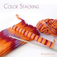 an orange and purple striped sock sitting next to a ball of yarn with a pair of scissors