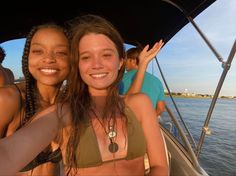 two women on a boat in the water with one holding her head up and smiling at the camera