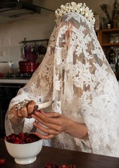 a woman wearing a veil and holding a bowl of cherries