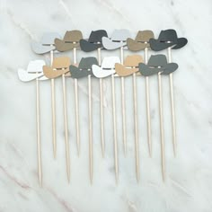 six wooden picks with different shapes and colors on top of a white marble countertop