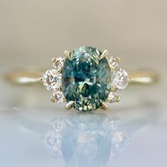 an oval blue diamond surrounded by three smaller white diamonds on a gold plated ring