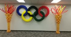 the olympic rings are made out of beads and plastic balls in an office cubicle