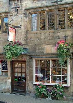 an old stone building with flower boxes on the front and side windows, along with potted plants