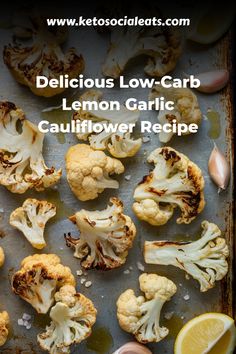 Roasted cauliflower florets with lemon slices and garlic cloves on a baking sheet.