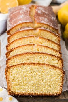 a loaf of lemon pound cake sitting on top of a wooden cutting board next to sliced lemons