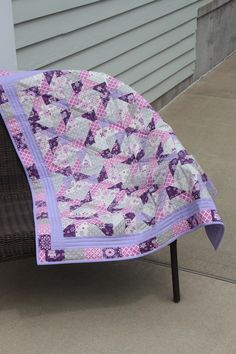 a purple and white quilt sitting on top of a chair