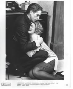 black and white photograph of two people sitting on the floor hugging each other in front of a stove