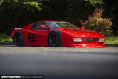 a red sports car is parked on the side of the road in front of some trees