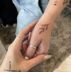 two people holding hands with tattoos on their fingers and one has a flower tattoo on it