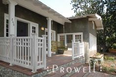 the front porch of a house with white railings and woodwork steps leading up to it