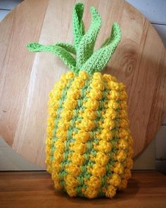 a crocheted pineapple sitting on top of a wooden table next to a round object