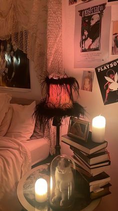 a table with books and candles on top of it in front of a wall full of pictures