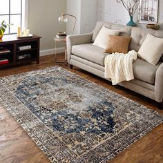 a living room filled with furniture and a rug on top of a hard wood floor