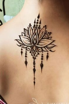 the back of a woman's neck with an intricate tattoo design on her chest