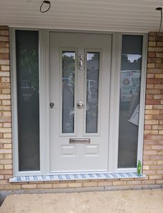 a white double door with two sidelights and glass panels on the front of a brick building