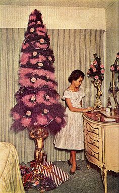 a woman standing next to a pink christmas tree