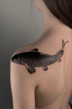 a woman's shoulder with a fish tattoo on it