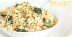 a white bowl filled with broccoli and chicken casserole on top of a wooden table