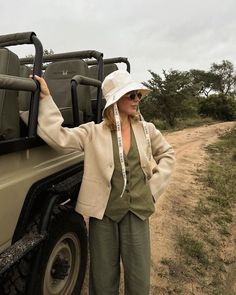 a woman standing in front of a truck on a dirt road