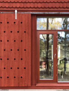 a red building with two windows and a cat sitting on the window sill