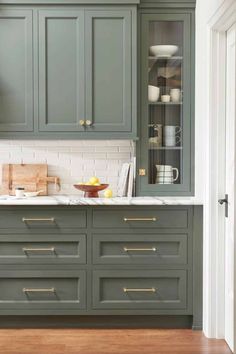 a kitchen with green cabinets and white counter tops