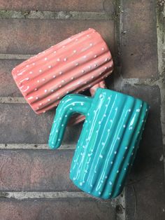 two ceramic mugs sitting on top of each other in the shape of cactuses