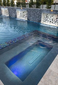 an empty swimming pool with blue water and decorative tile around the edge is pictured in this image