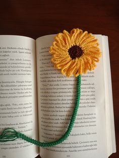 an open book with a crocheted sunflower on the page and string attached to it