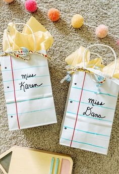 two paper bags with writing on them sitting on the floor next to some pom poms