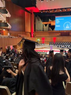 a group of people in graduation gowns and caps at a stage with an audience