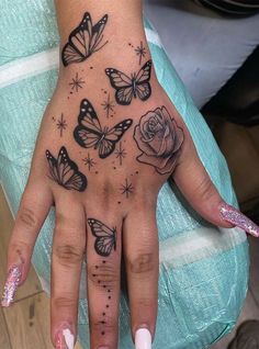 a woman's hand with butterflies and roses tattooed on the middle of her palm