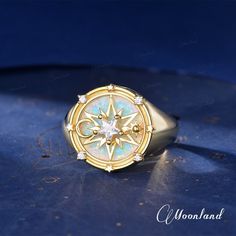 a gold ring with an opal and diamond in the center on a blue surface