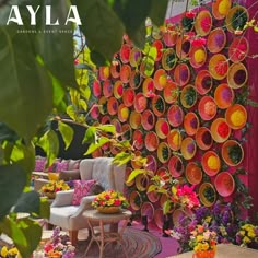 an outdoor seating area is decorated with colorful flowers and plates on the wall, along with chairs and tables