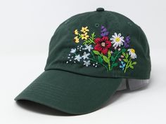 a green hat with flowers embroidered on the front and side, sitting against a white background