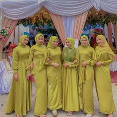 four women in lime green dresses standing next to each other under a tent with white drapes