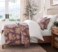 a bed with purple and white comforter in a bedroom next to a window overlooking the mountains