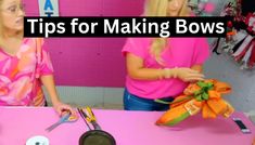 two women in pink shirts are making bows with scissors and other items on a table