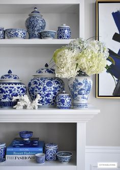 blue and white vases, books, and flowers are on the shelves in this room