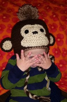 a baby wearing a monkey hat sitting on top of a bed