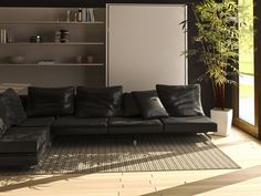 a black leather couch sitting on top of a wooden floor next to a book shelf