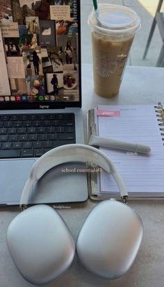 an open laptop computer sitting on top of a table next to headphones and a cup of coffee