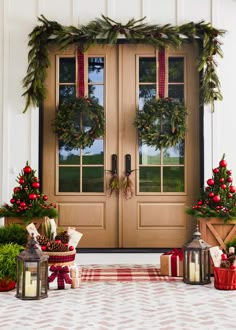 two christmas wreaths are on the front door and one is decorated with greenery