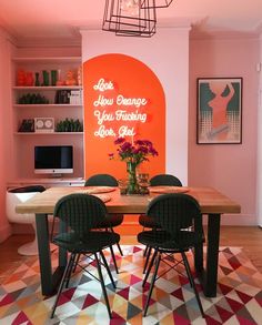 a dining room table with chairs and an orange sign on the wall