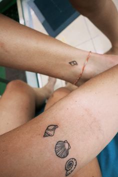 a woman's legs with tattoos on them and seashells in the background