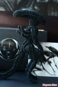 a black rope figurine sitting on top of a table next to a camera