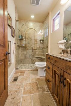 a bathroom with a walk in shower sitting next to a sink and a wooden cabinet